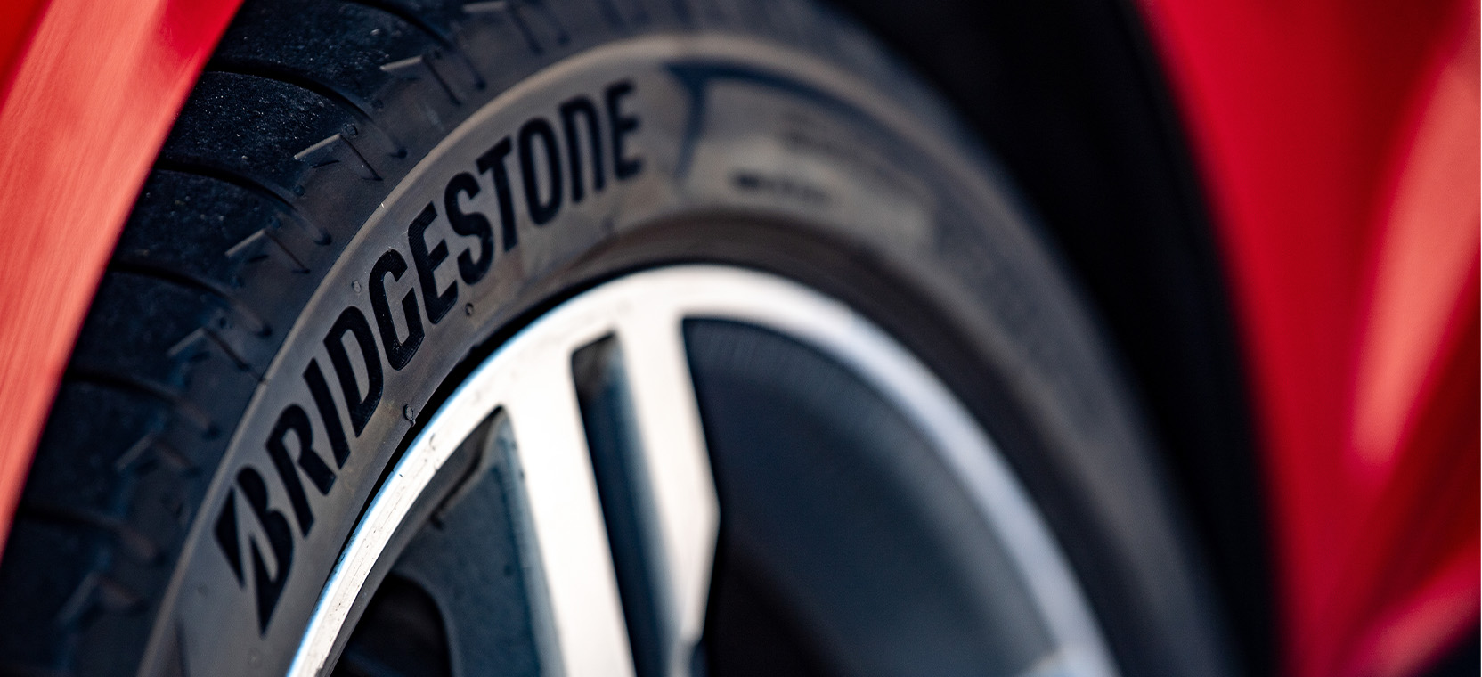 Primer plano de un neumático Bridgestone montado en un vehículo rojo